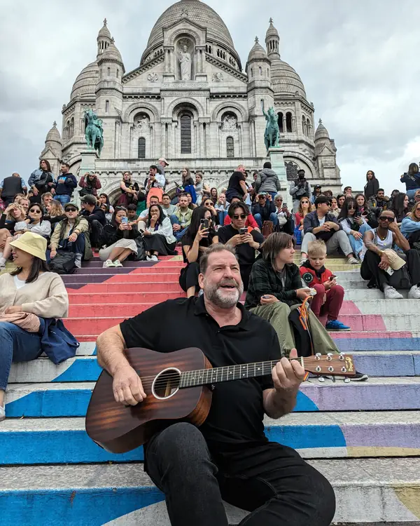 Arnold Rutjens speelt gitaar en zingt op de trappen van de Sacré-Cœur in Montmartre, Parijs