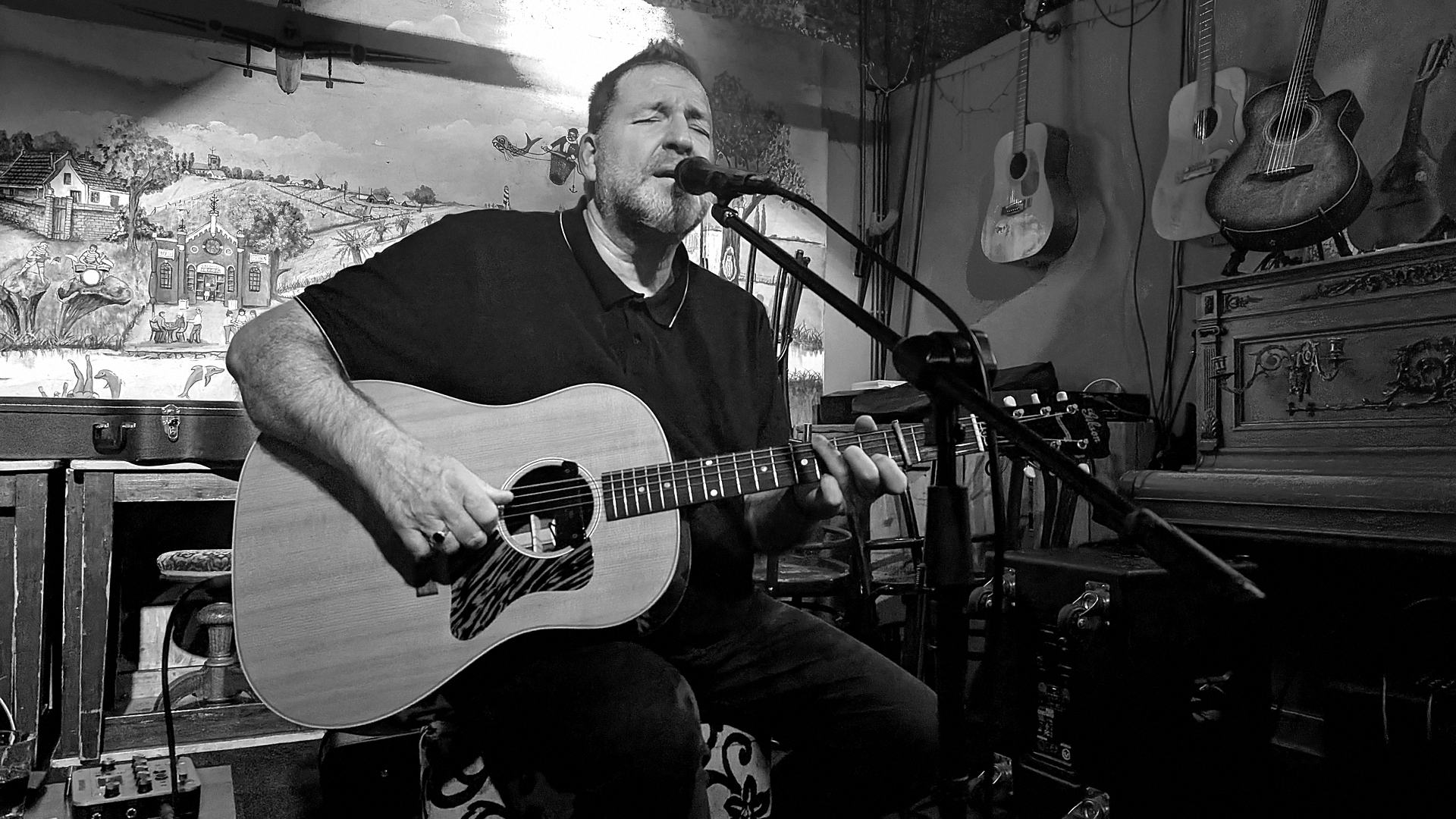 Arnold Rutjens zingt en speelt gitaar, live in een café