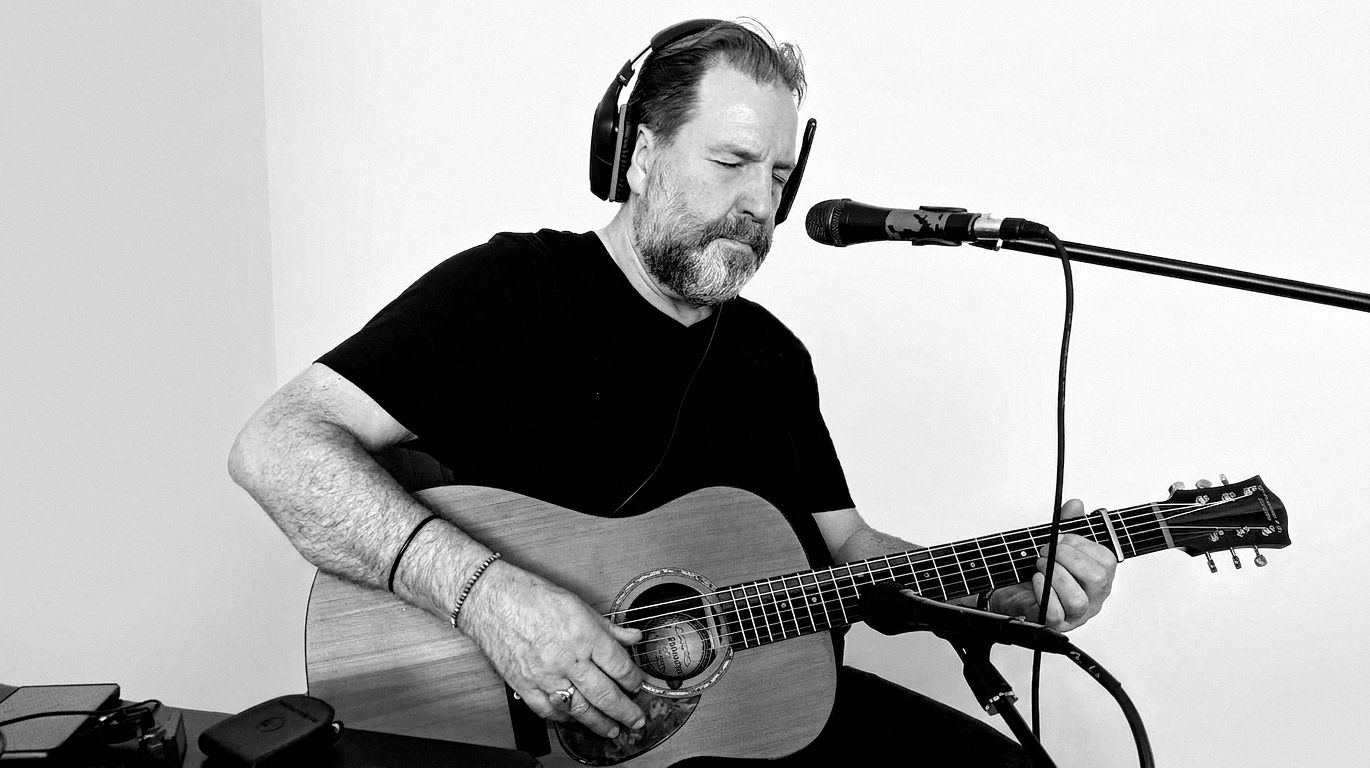 Arnold Rutjens singing and playing guitar at the microphone